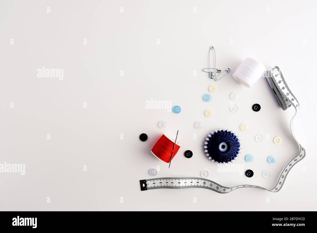 measuring tape, yarns, needles, safety pins, buttons, arranged on white background Stock Photo