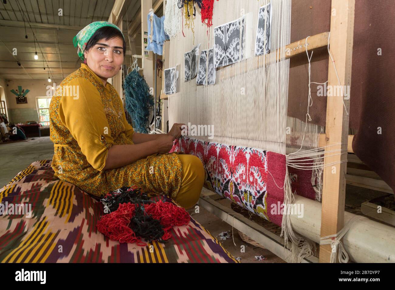 Uzbek woman in local clothes weaving, in Margilan, Uzbekistan. Stock Photo