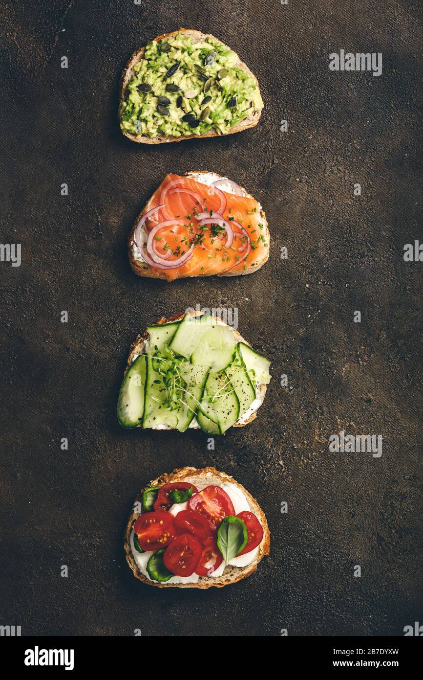 Variety of sandwiches for breakfast, snack, appetizers - avocado puree, mozzarella, tomatoes, basil, cream cheese, smoked salmon, red onion, cucumber Stock Photo