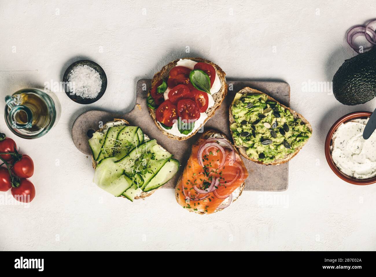 Variety of sandwiches for breakfast, snack, appetizers - avocado puree, mozzarella, tomatoes, basil, cream cheese, smoked salmon, red onion, cucumber Stock Photo