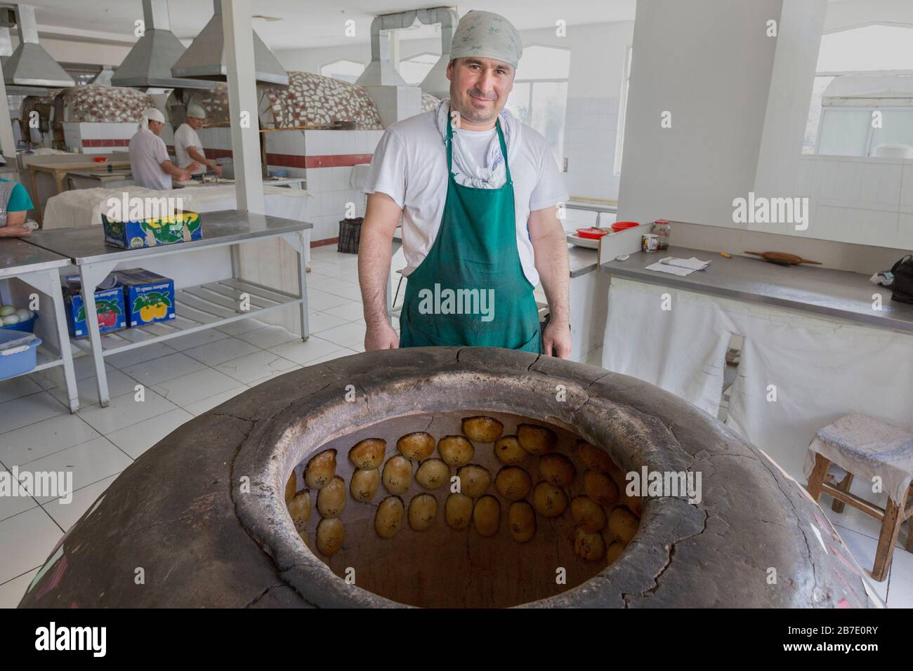 Uzbek vendor baking local pastry known as Samsa, in Chorsu Bazaar, Tashkent, Uzbekistan. Stock Photo
