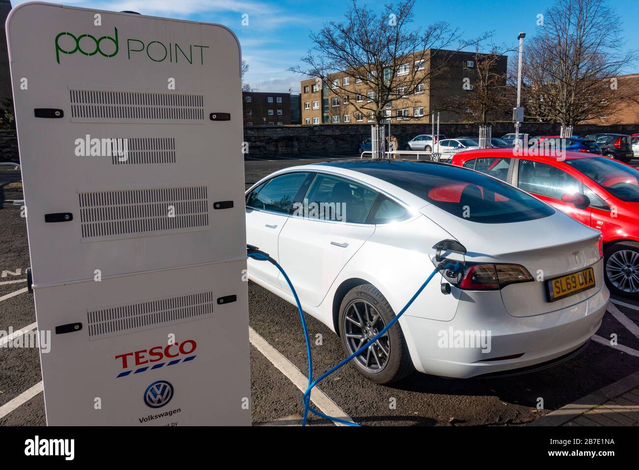 Tesla electric car charging at free Pod Point charging station in Tesco supermarket, UK, United Kingdom Stock Photo