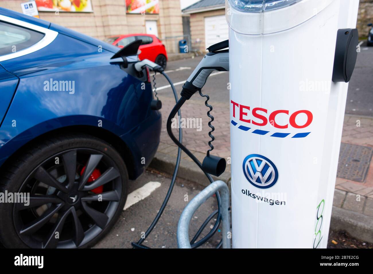 Tesla electric car charging at free charging station in Tesco supermarket, UK, United Kingdom Stock Photo