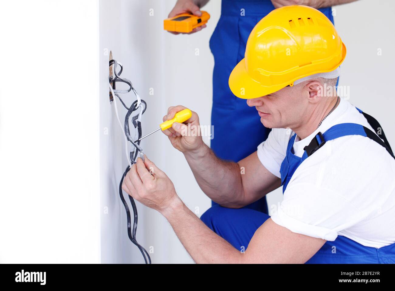 Electrician put electrical wires for wall socket using screw driver Stock Photo