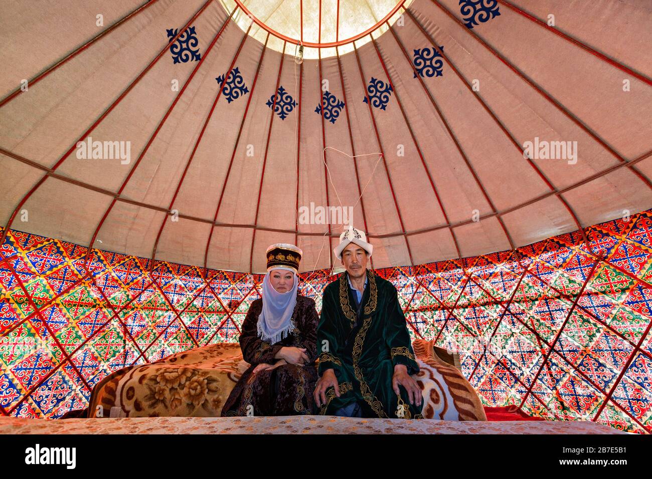 Kyrgyz couple in national costumes, in a nomadic tent known as yurt, near the city of Bishkek, Kyrgyzstan Stock Photo