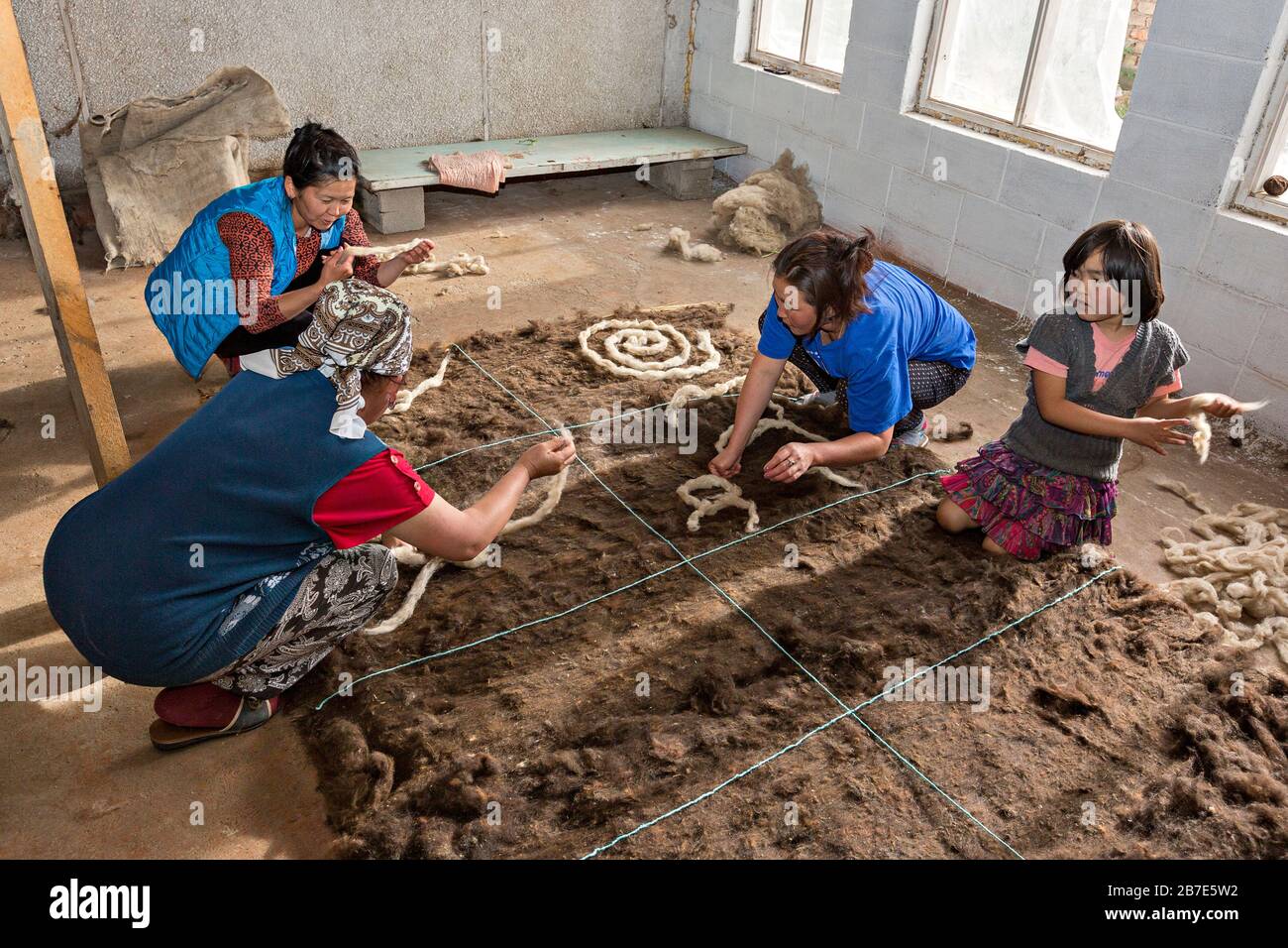 Local people making felt carpet in traditional way, in Issyk Kul, Kyrgyzstan Stock Photo