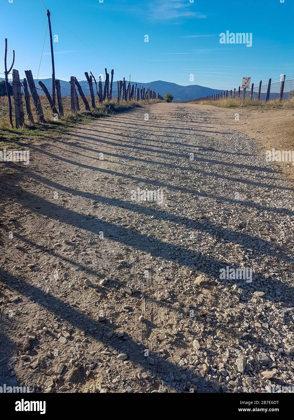 wide dirt road bordered by a fence Stock Photo