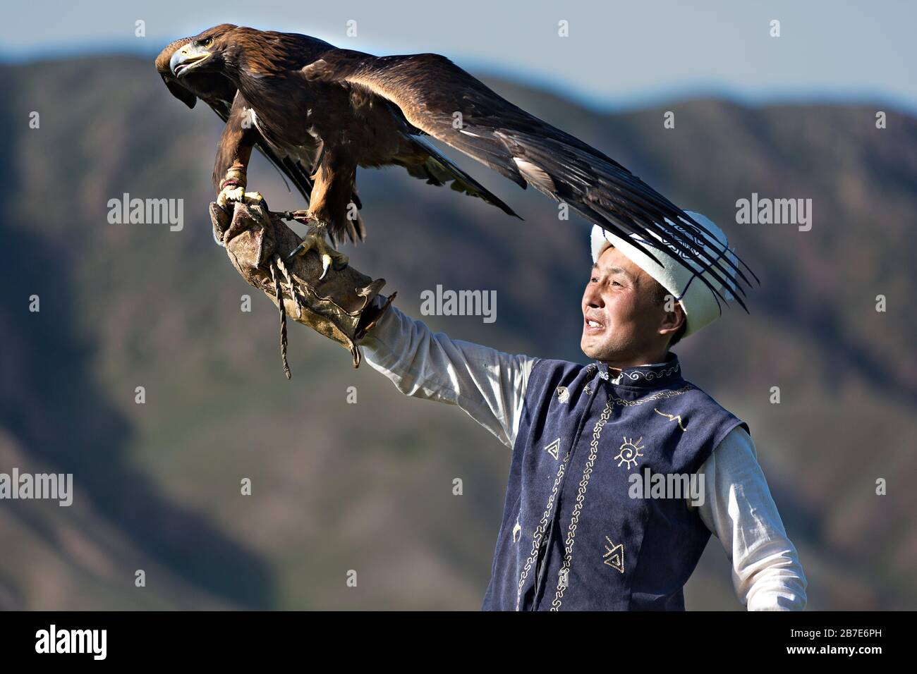 Golden eagle trainer holding his eagle Issyk Kul Lake, Kyrgyzstan Stock Photo