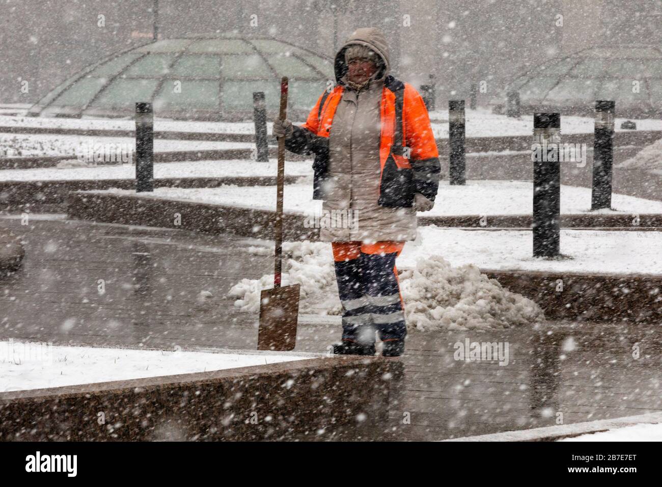Moscow, Russia - March, 15th, 2020: An employee of communal services removes snow during abnormal snowfall on Manege square in the downtown of Moscow, Russia Stock Photo