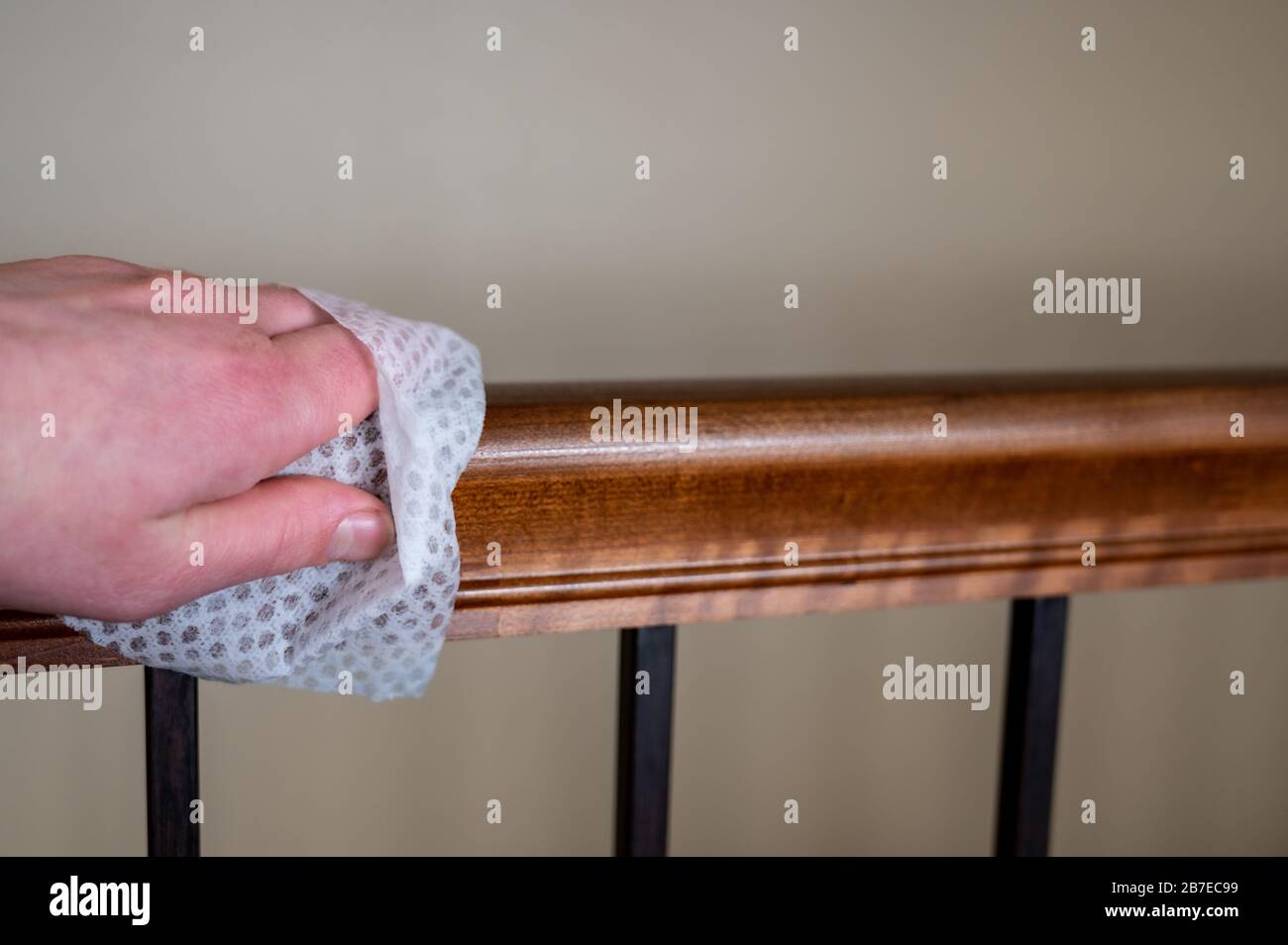 Caucasian hand with disinfecting wipe used for sanitizing a wooden ...
