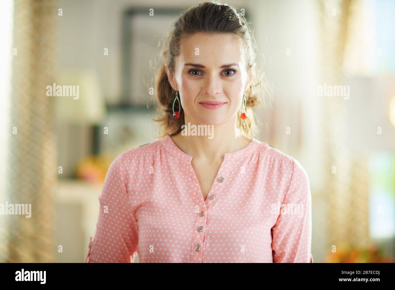 Portrait of young woman in a pink blouse at modern home in sunny day. Stock Photo