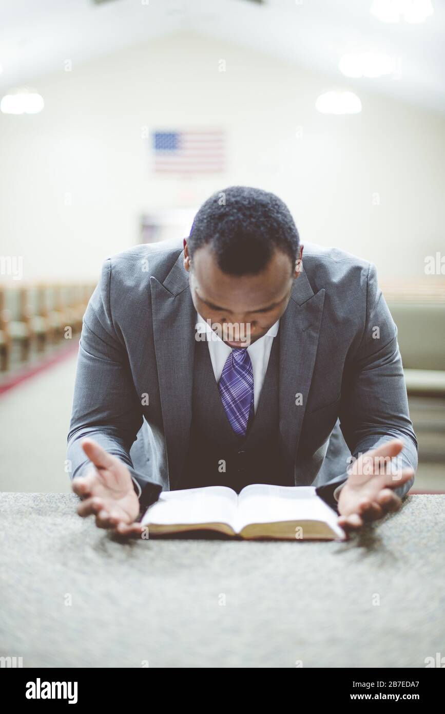 AfricanAmerican male praying with his head down looking at the Bible