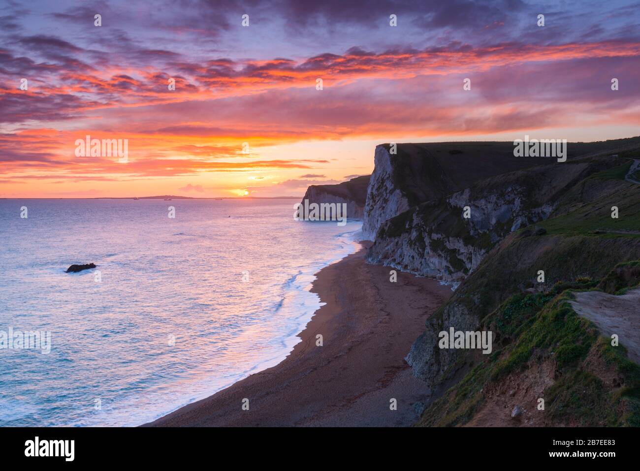 Durdle Door, Lulworth, Dorset, UK.  15th March 2020.  UK Weather.  A spectacular fiery sunset at Durdle Door on the Dorset Jurassic Coast near Lulworth looking towards Swyre Head and Bats Head as the cloud clears as high pressure builds in from the South West.  Picture Credit: Graham Hunt/Alamy Live News Stock Photo