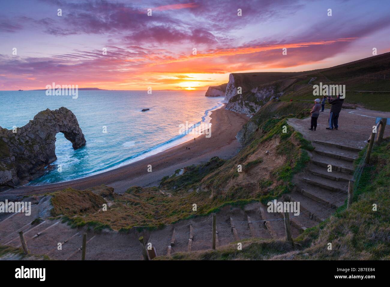 Durdle Door, Lulworth, Dorset, UK.  15th March 2020.  UK Weather.  Onlookers watching the spectacular sunset at Durdle Door on the Dorset Jurassic Coast near Lulworth as the cloud clears as high pressure builds in from the South West.  Picture Credit: Graham Hunt/Alamy Live News Stock Photo