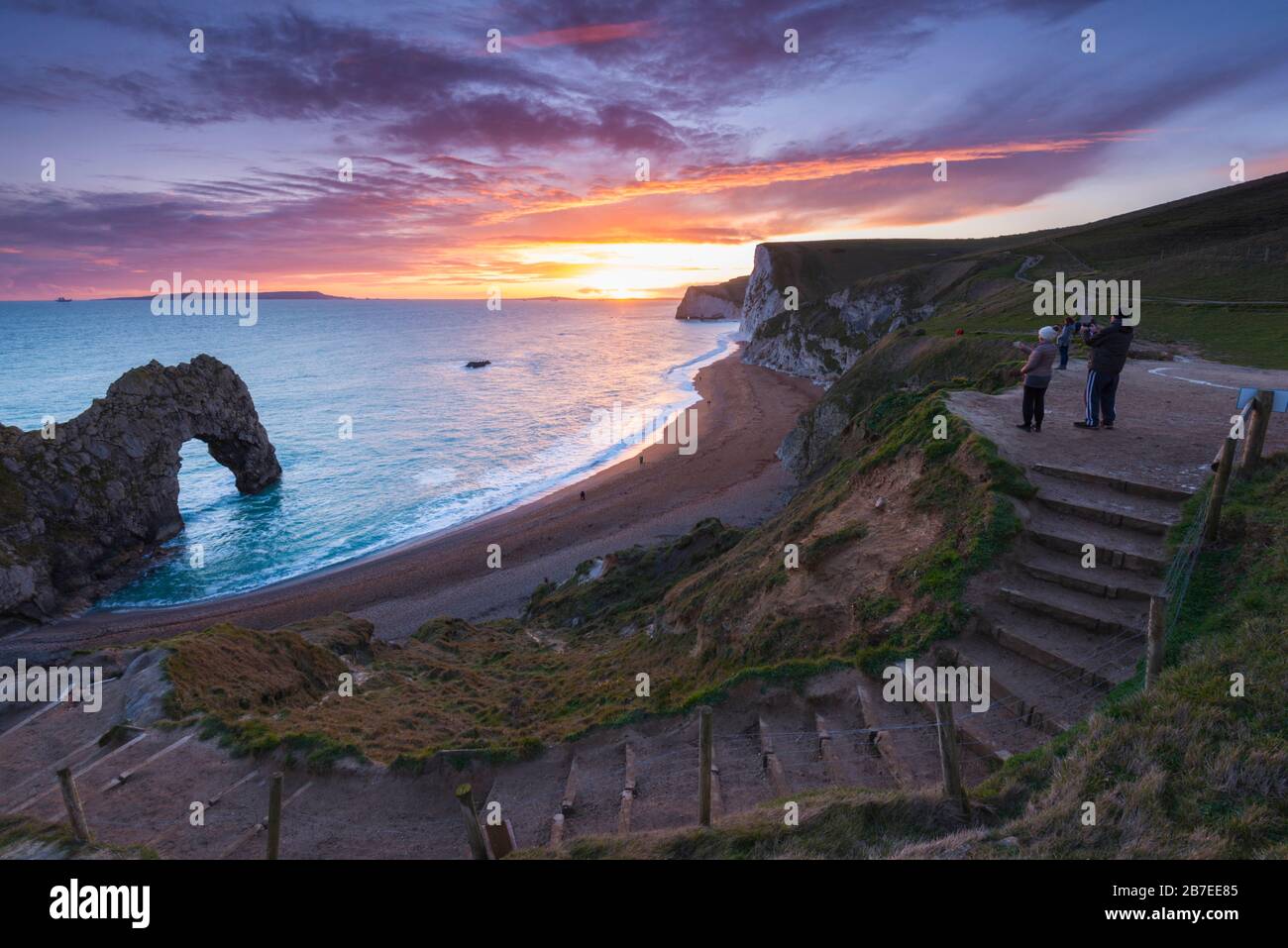 Durdle Door, Lulworth, Dorset, UK.  15th March 2020.  UK Weather.  Onlookers watching the spectacular sunset at Durdle Door on the Dorset Jurassic Coast near Lulworth as the cloud clears as high pressure builds in from the South West.  Picture Credit: Graham Hunt/Alamy Live News Stock Photo