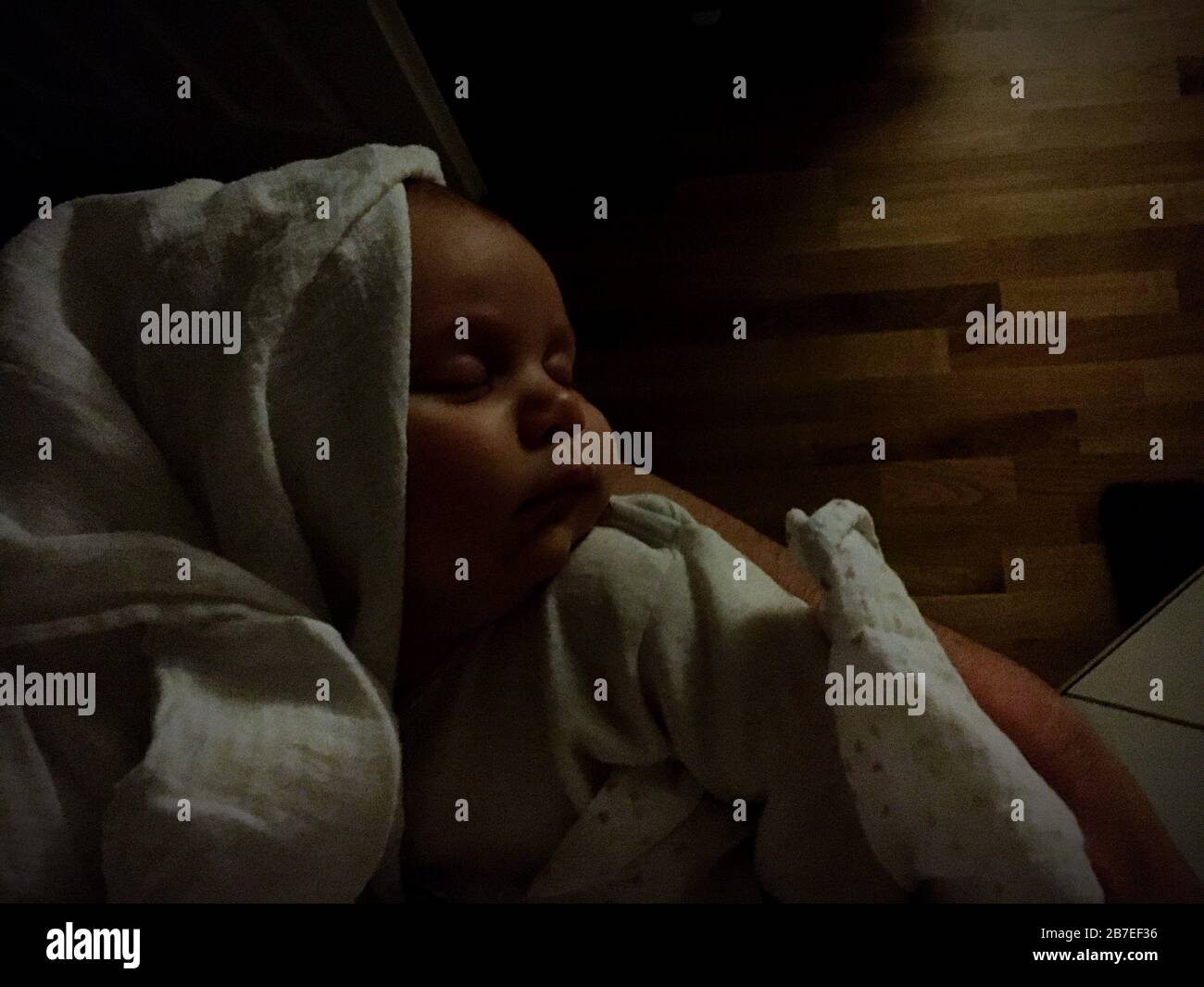 Baby covered in sheets sleeping in a dark room Stock Photo Alamy