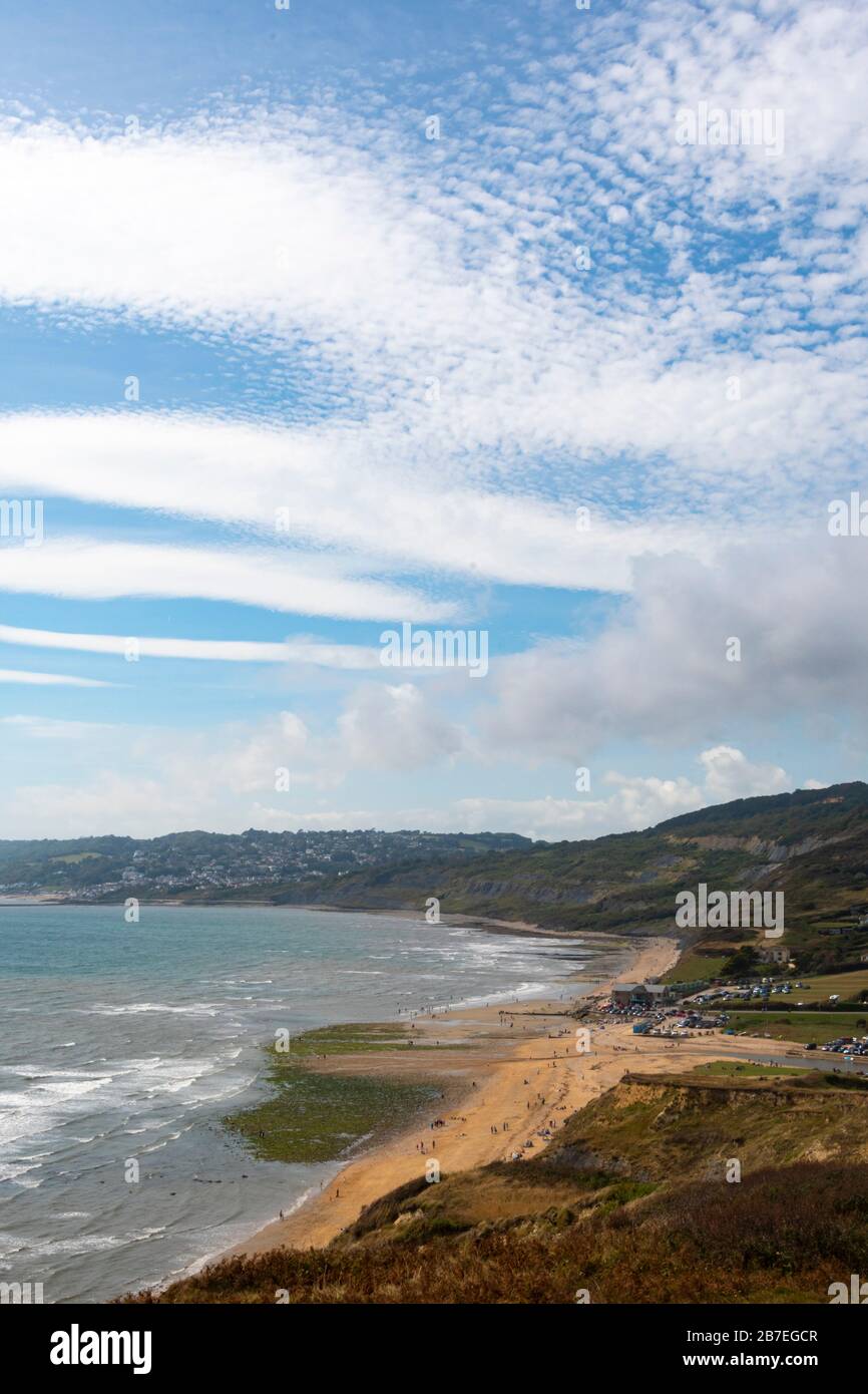 Charmouth Beach from coastal path along hillside, Charmouth, Dorset, England.  White clouds in blue sky, Stock Photo