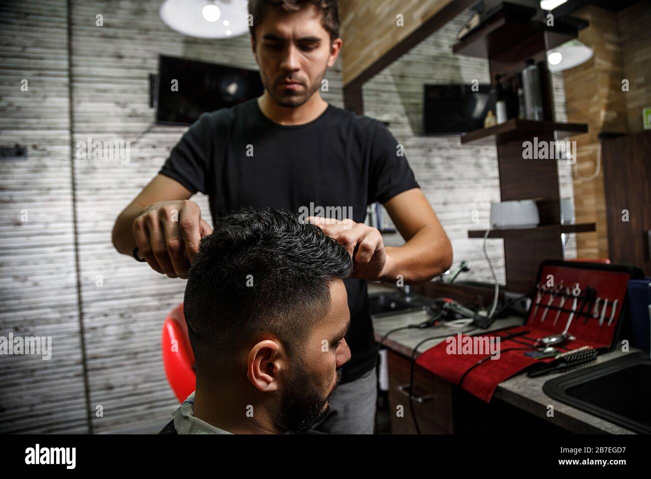 a brutal-looking Barber cuts the hair of an Indian guy. cinematic image Stock Photo - Alamy a brutal-looking Barber cuts the hair of an Indian guy. cinematic image Stock Photo - Alamy