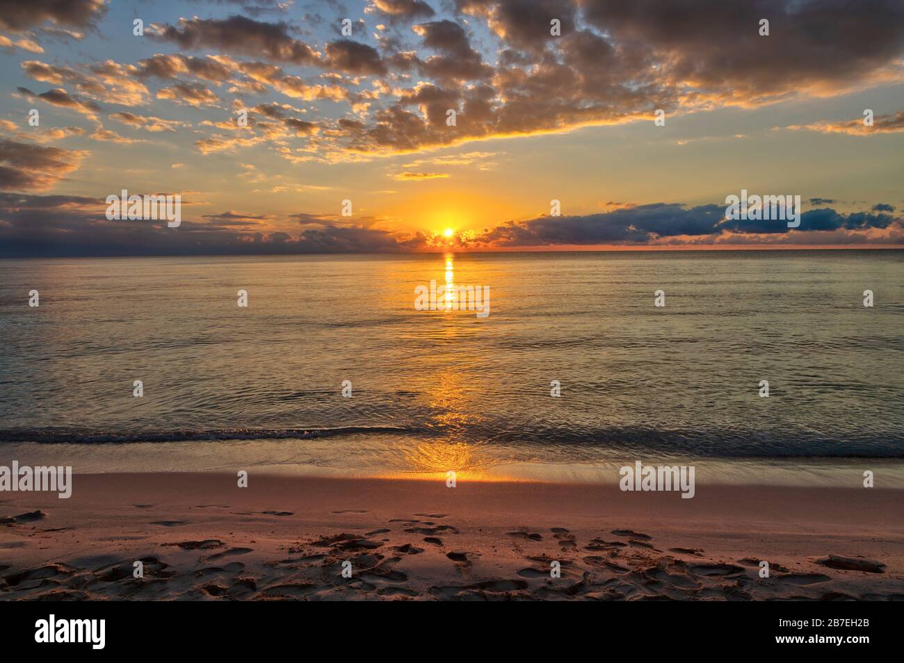 Beautiful sunrise by the beach at Cancun, Mexico, with golden reflections on Caribbean Sea. Stock Photo