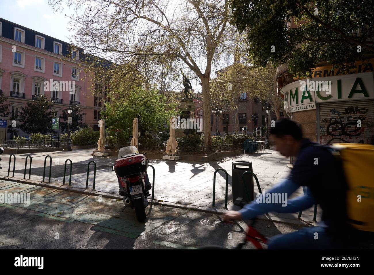 A glovo home delivery biker is the only thing person passing through empty Kings Square in Madrid as a result of the state of emergency lockdown Stock Photo
