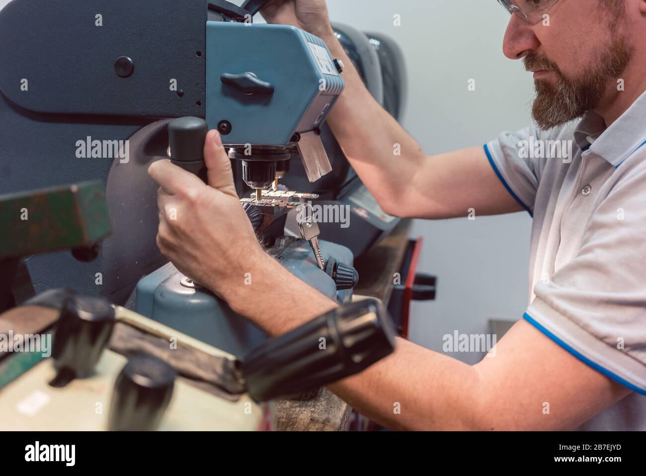 Locksmith cutting key with his machine Stock Photo