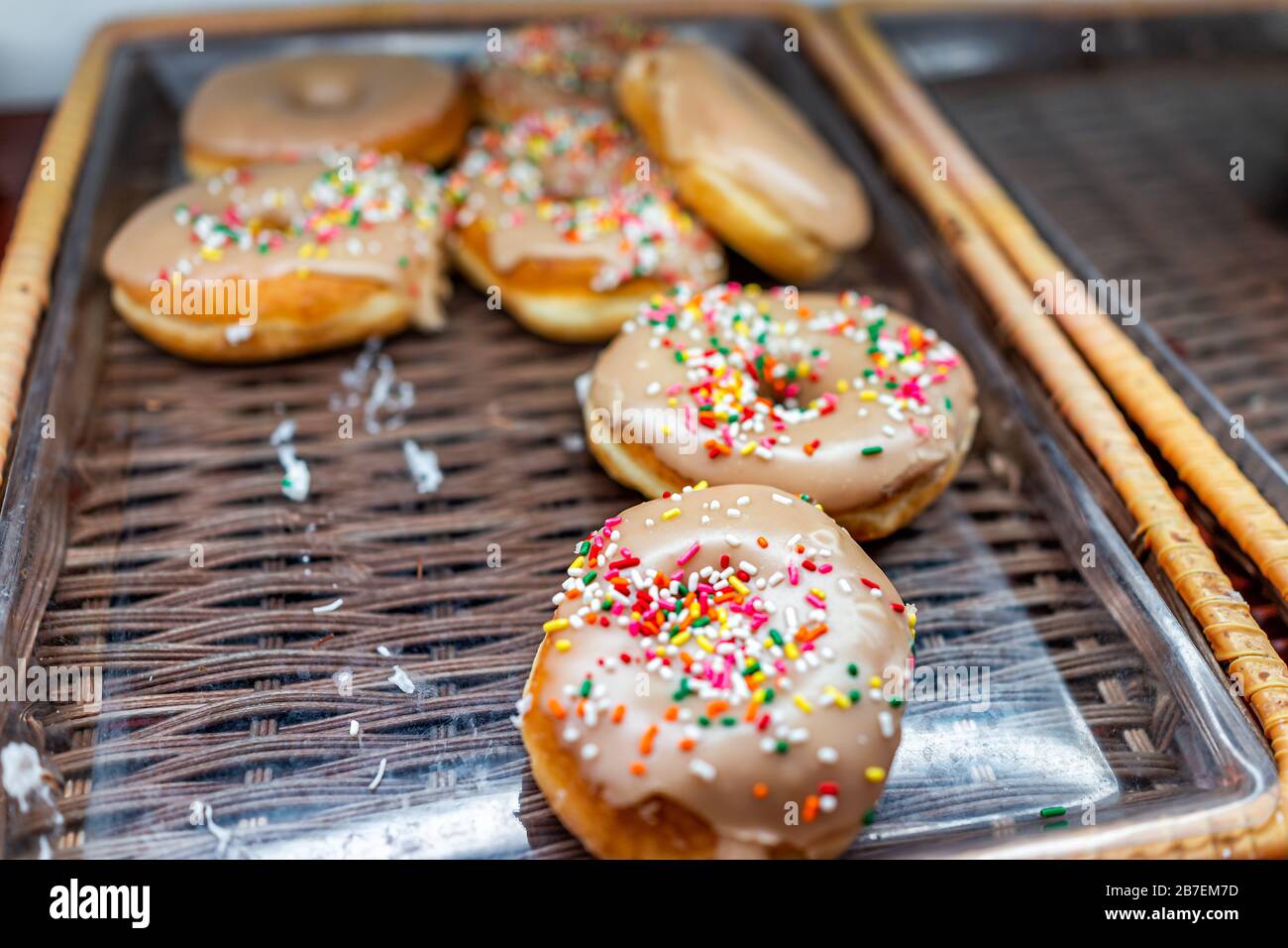 Brown icing donuts with pink sprinkles closeup on bakery tray deep