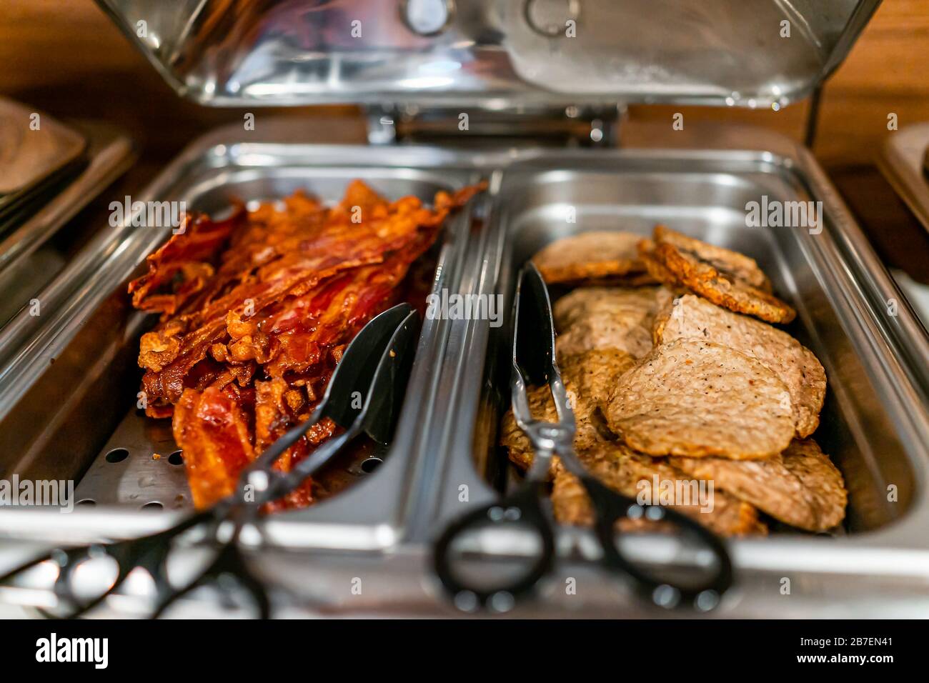 Fresh hot buffet tray with tongs to serve food bacon and sausage in