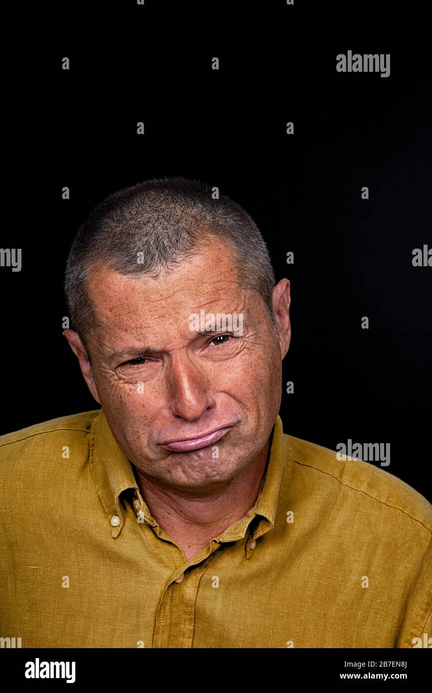 Portrait of a Man with grotesque emotions on a black background Stock Photo