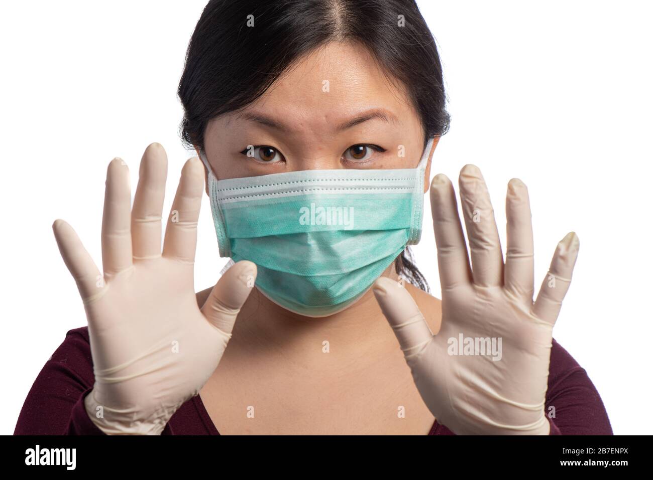 young asiatic woman wearing a green protection mask with medical gloves making stop sign on a white background Stock Photo
