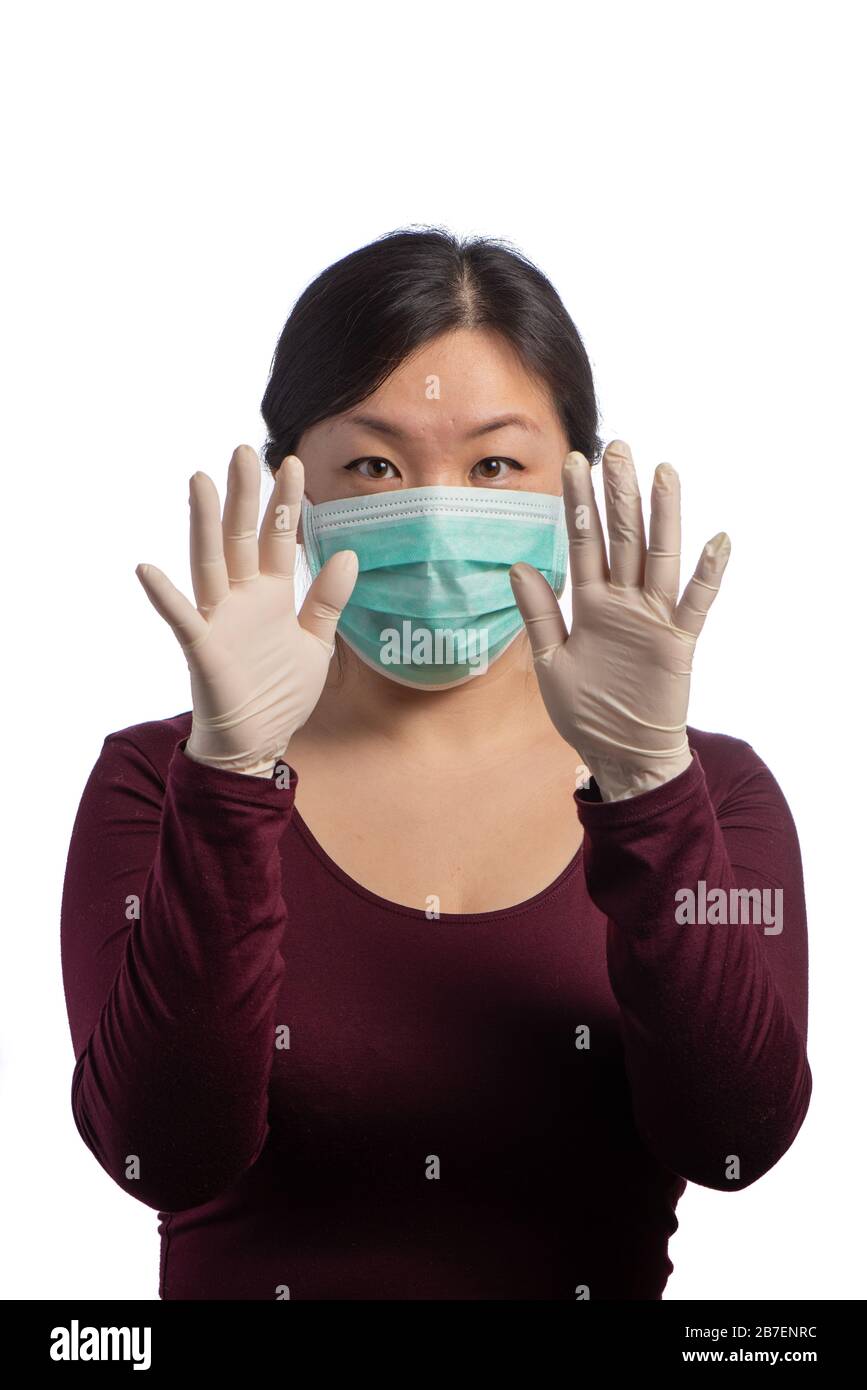 young asiatic woman wearing a green protection mask with medical gloves making signs with its hands on a white background Stock Photo