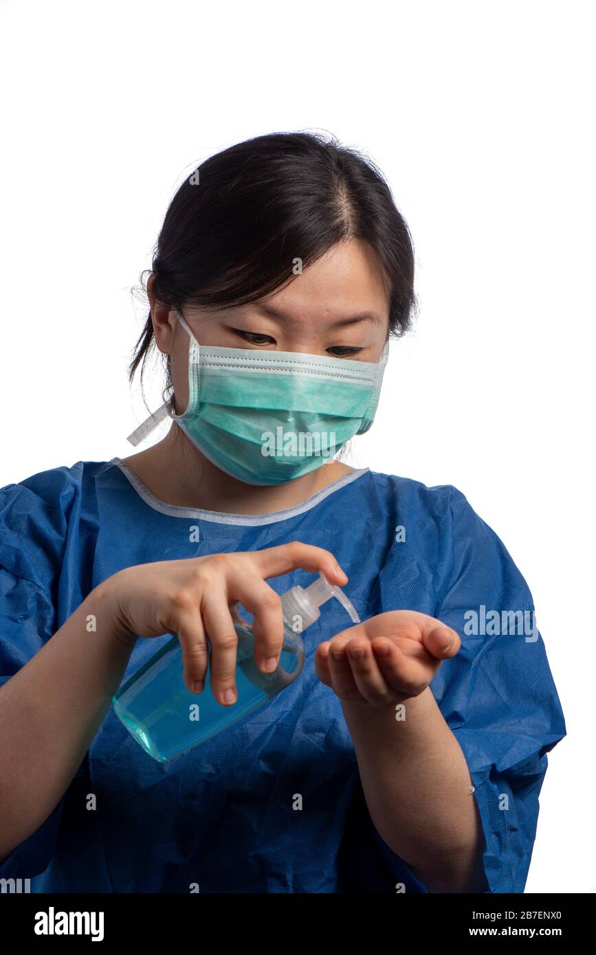 Young asiatic physician woman wearing a green protection mask  using hand sanitizer on a white background Stock Photo