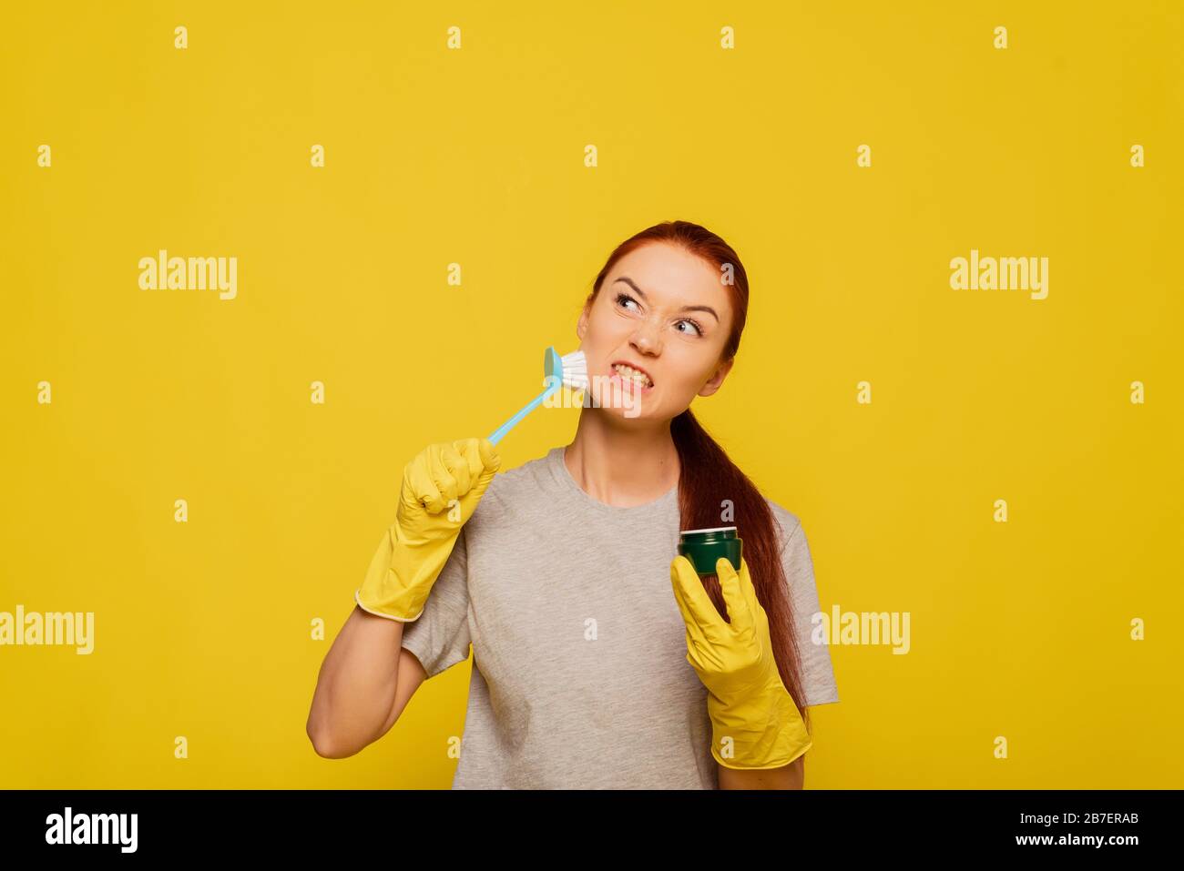 Beauty Face Skin Care. Closeup Young Woman In Yellow Gloves And Cleaning Brush In Hand Exfoliating Skin. Portrait Of Beautiful Healthy Girl With Natural Makeup Scrubbing Facial Skin. Stock Photo