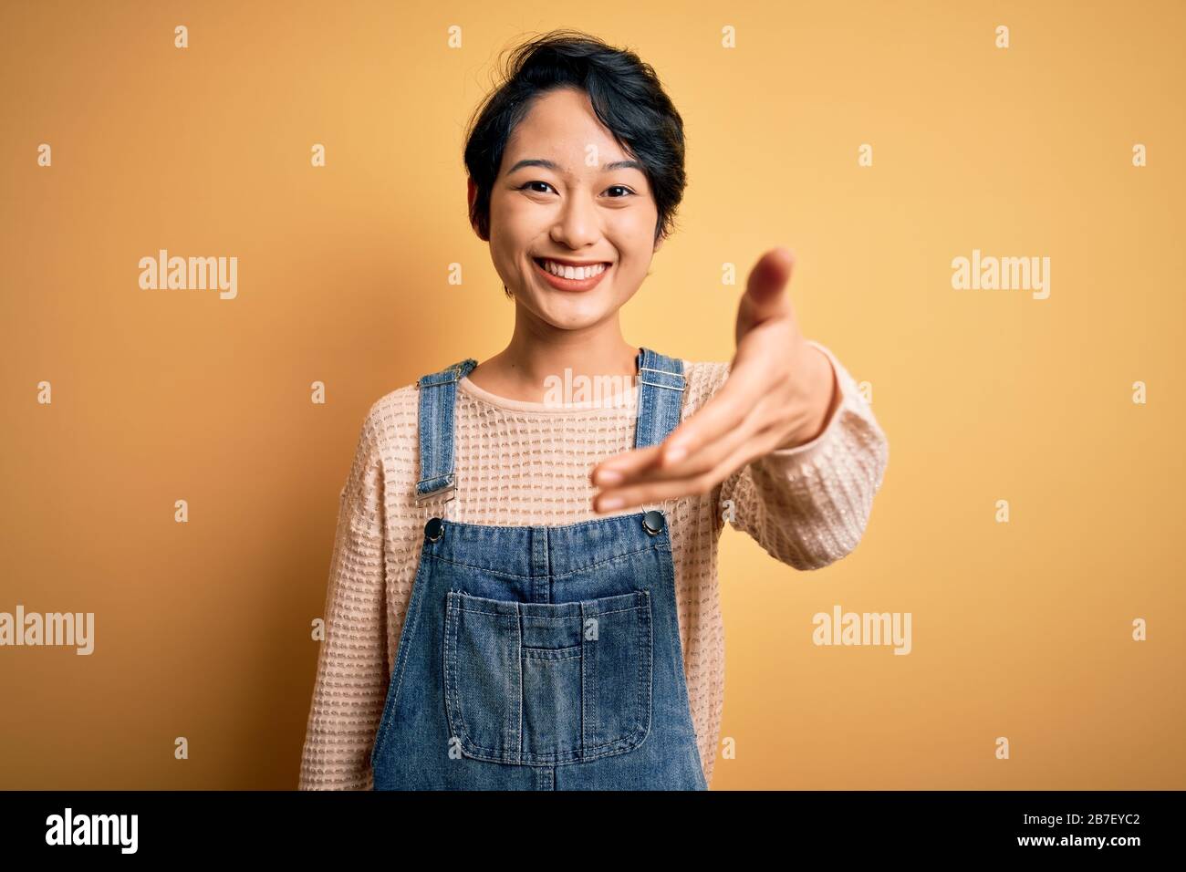 Young beautiful asian girl wearing casual denim overalls over isolated ...