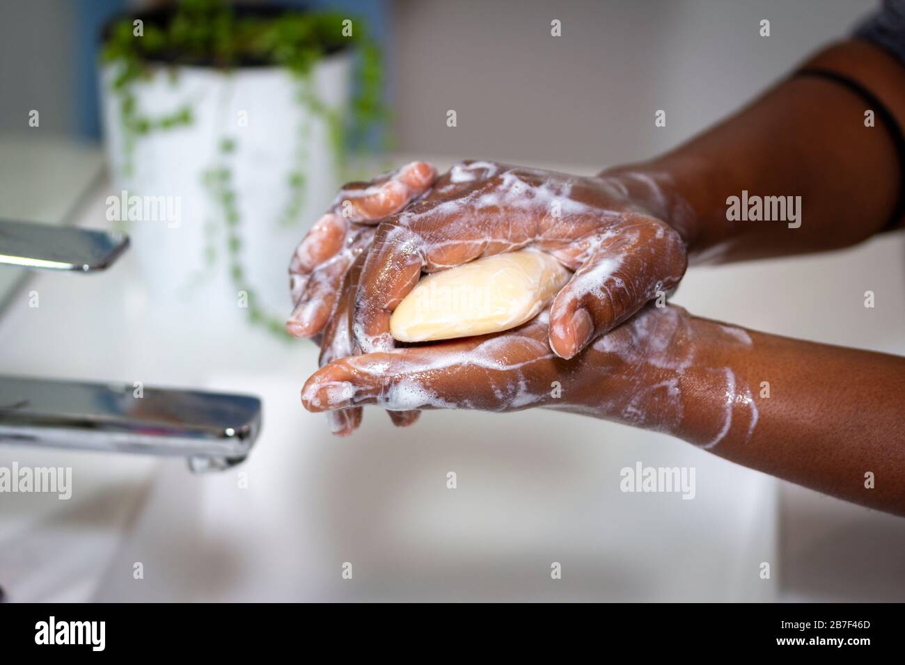 close up of black African woman washing hands with soap in sink Stock Photo