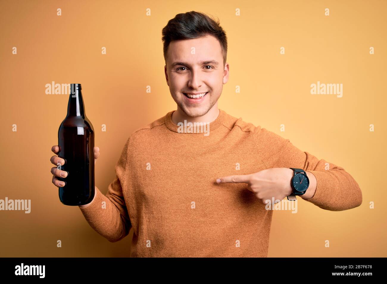 stopcontact Onverschilligheid onderwijs Young handsome caucasian man drinking a bottle of beer over yellow  background with surprise face pointing finger to himself Stock Photo - Alamy