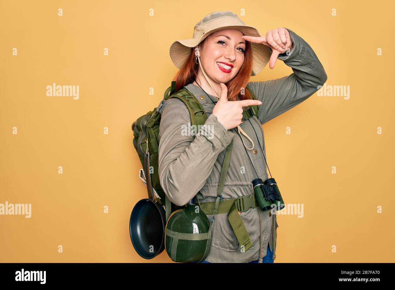 Young redhead backpacker woman hiking wearing backpack and hat over ...