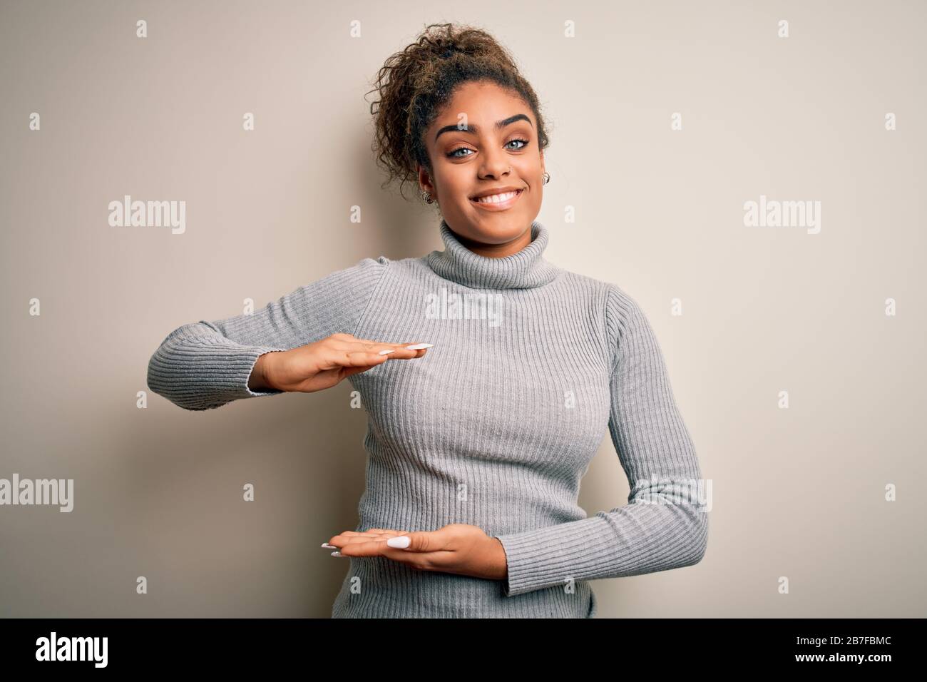 Beautiful african american girl wearing turtleneck sweater standing over  white background gesturing with hands showing big and large size sign,  measur Stock Photo - Alamy