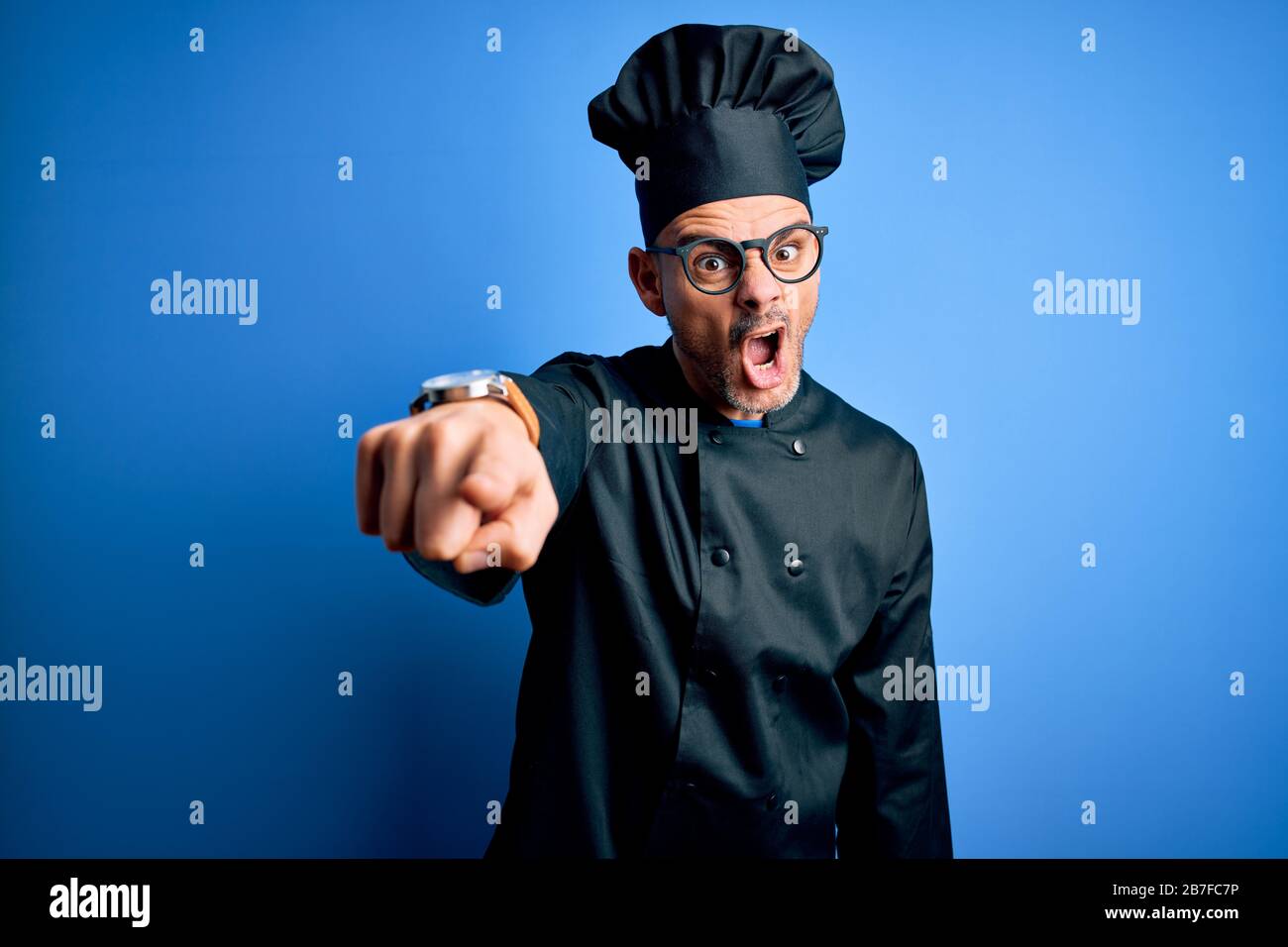 Young handsome chef man wearing cooker uniform and hat over isolated ...