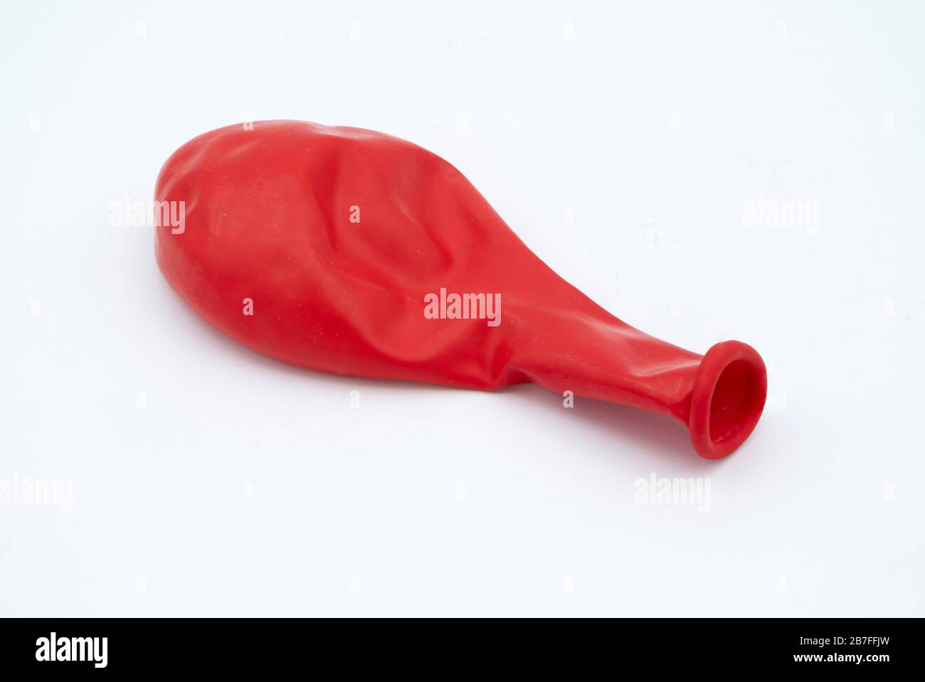 Deflated red baloon cut out isolated on white background Stock Photo