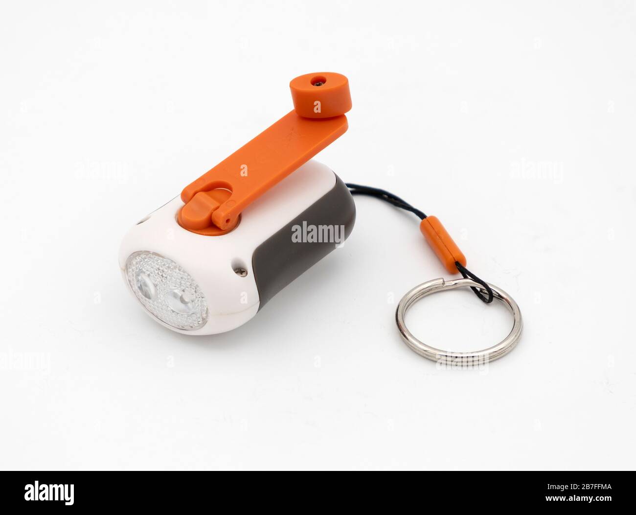 Small keychain size crank wind up flashlight with orange on/off button isolated on white background Stock Photo