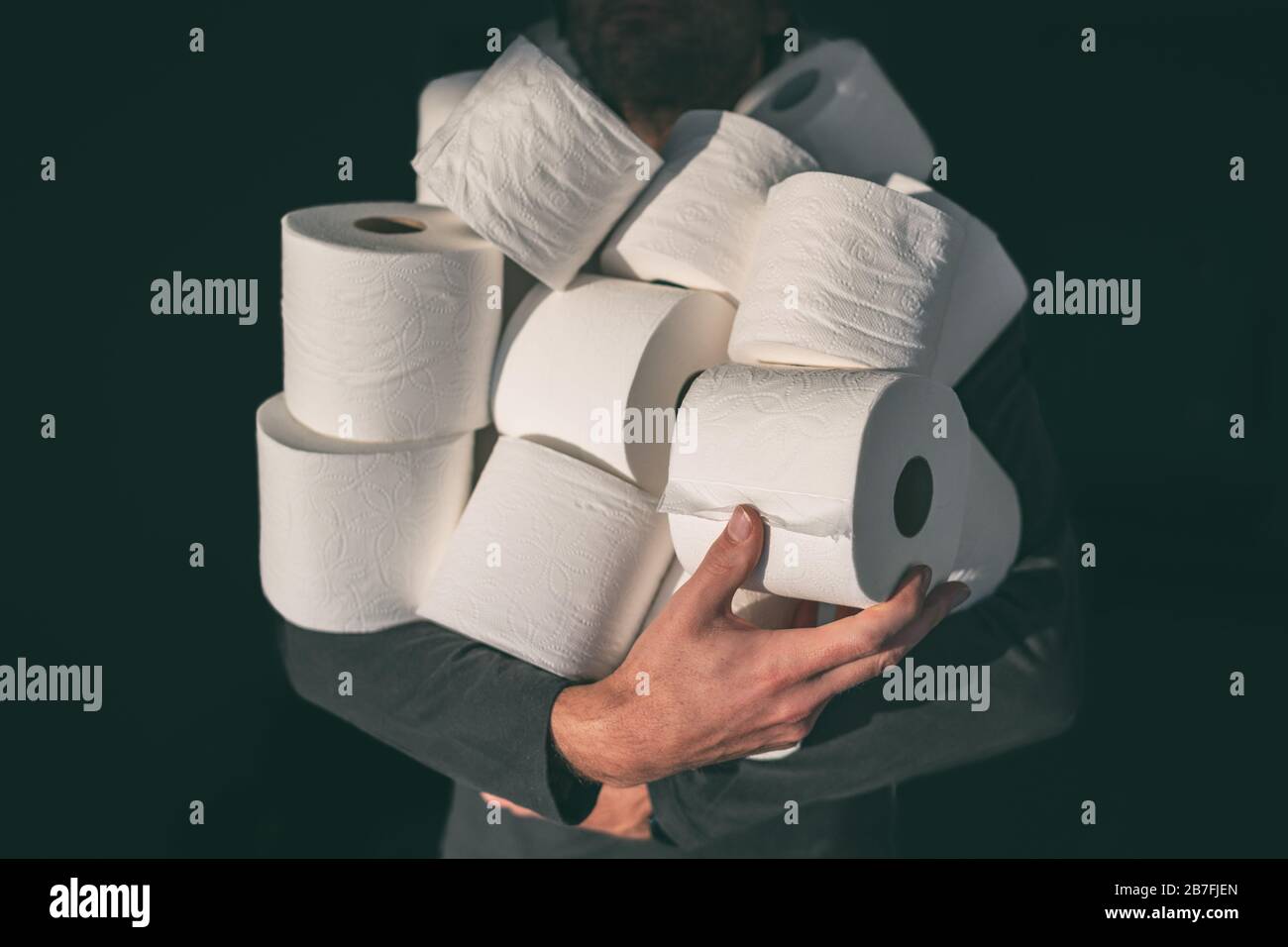 Toilet paper shortage coronavirus panic buying man hoarding carrying many rolls at home in fear of corona virus outbreak closing shopping stores. Stock Photo