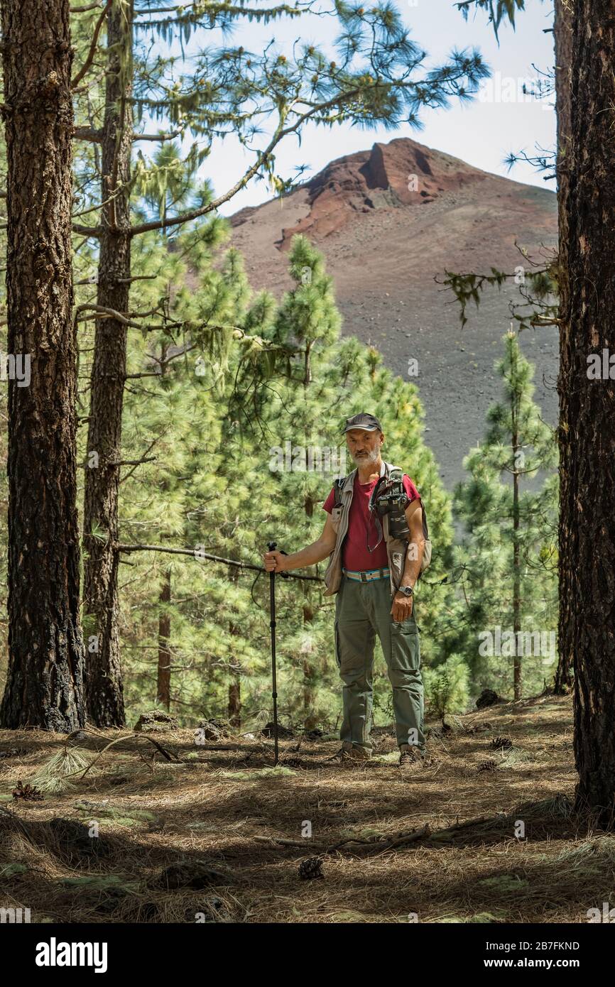 Traveler in a cap with backpack, hiking sticks has stopped to make a ...