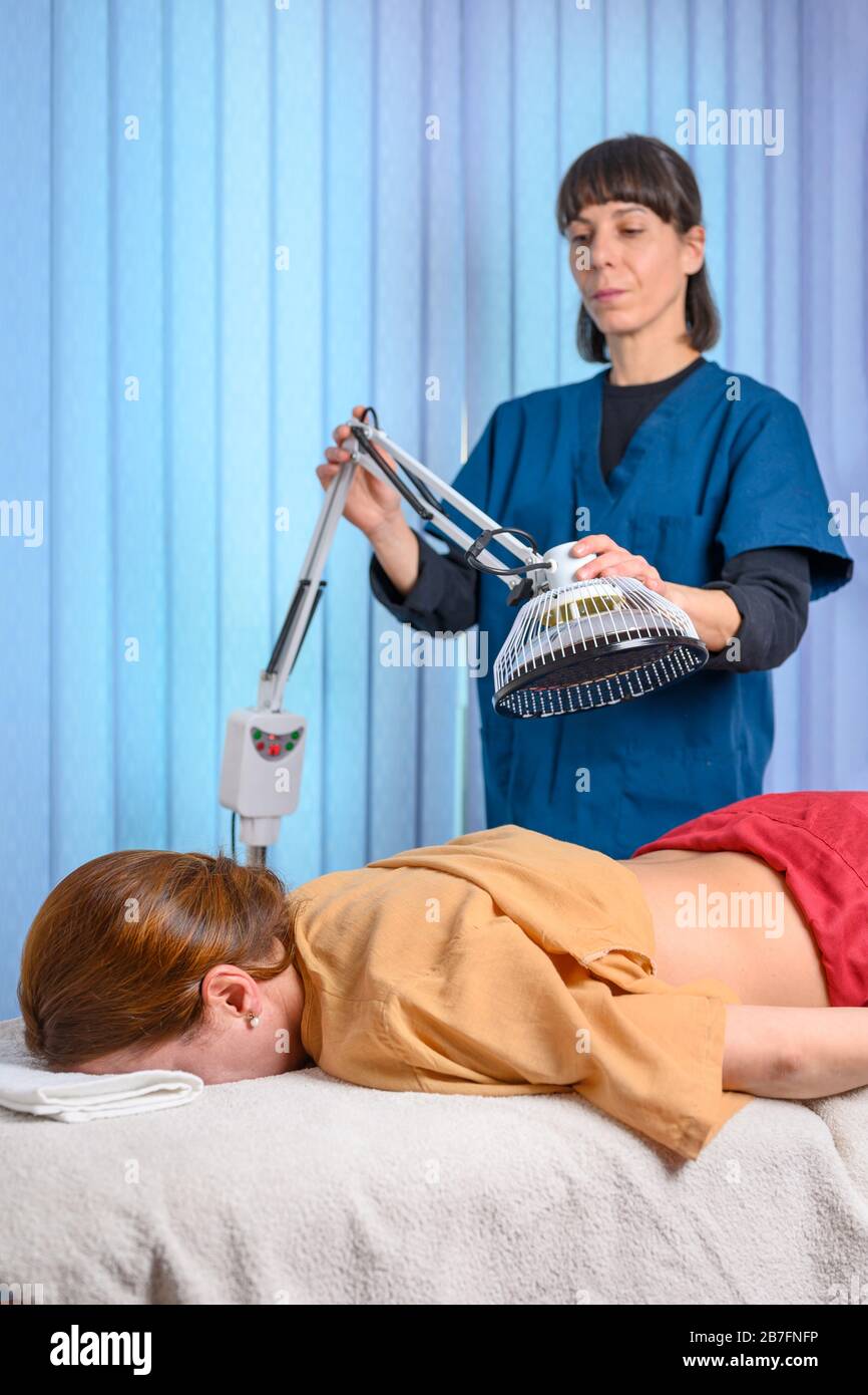 Therapist doing healing infrared treatment on woman back . Alternative