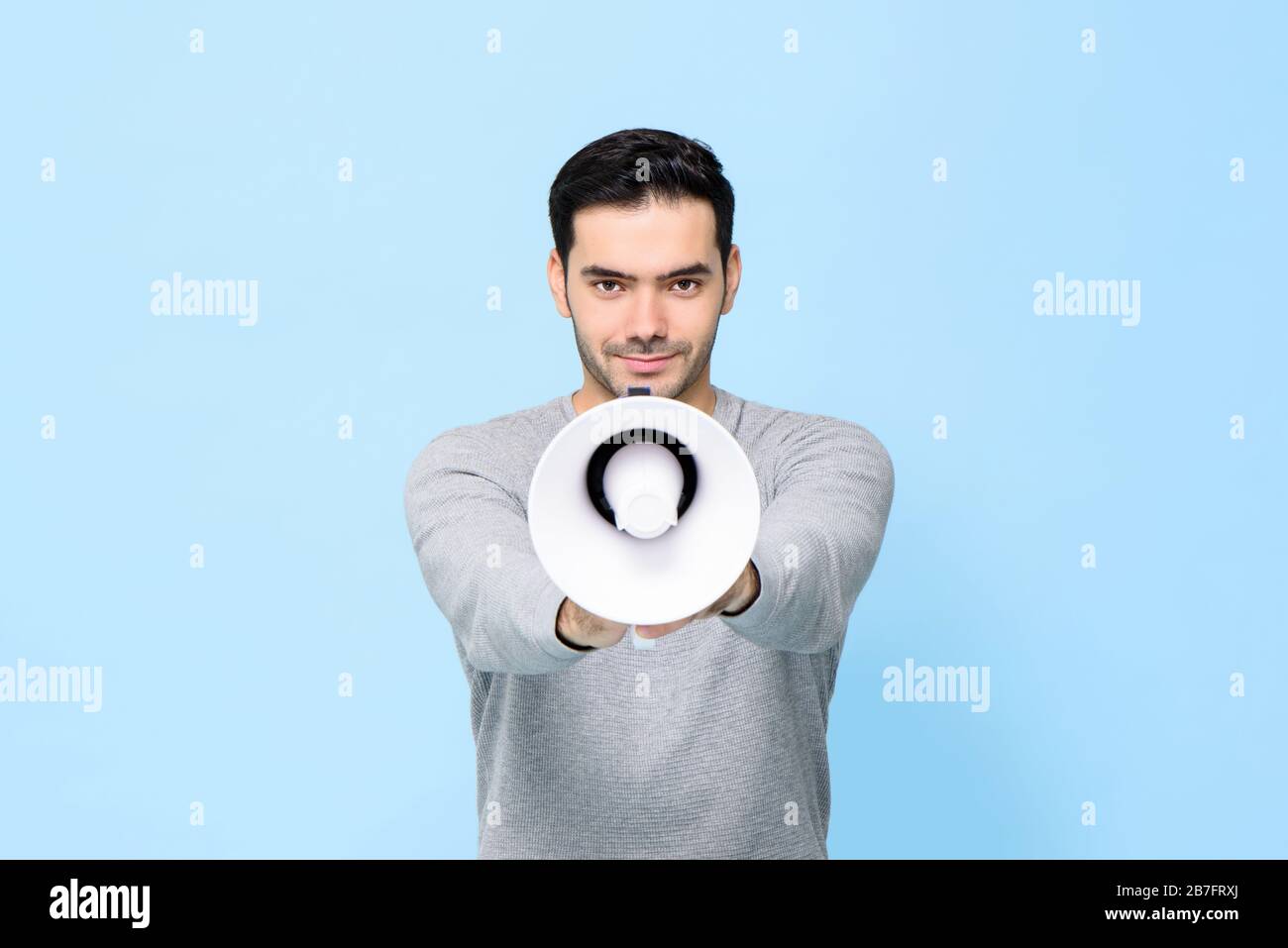 Young handsome man with megaphone isolated on light blue background Stock Photo