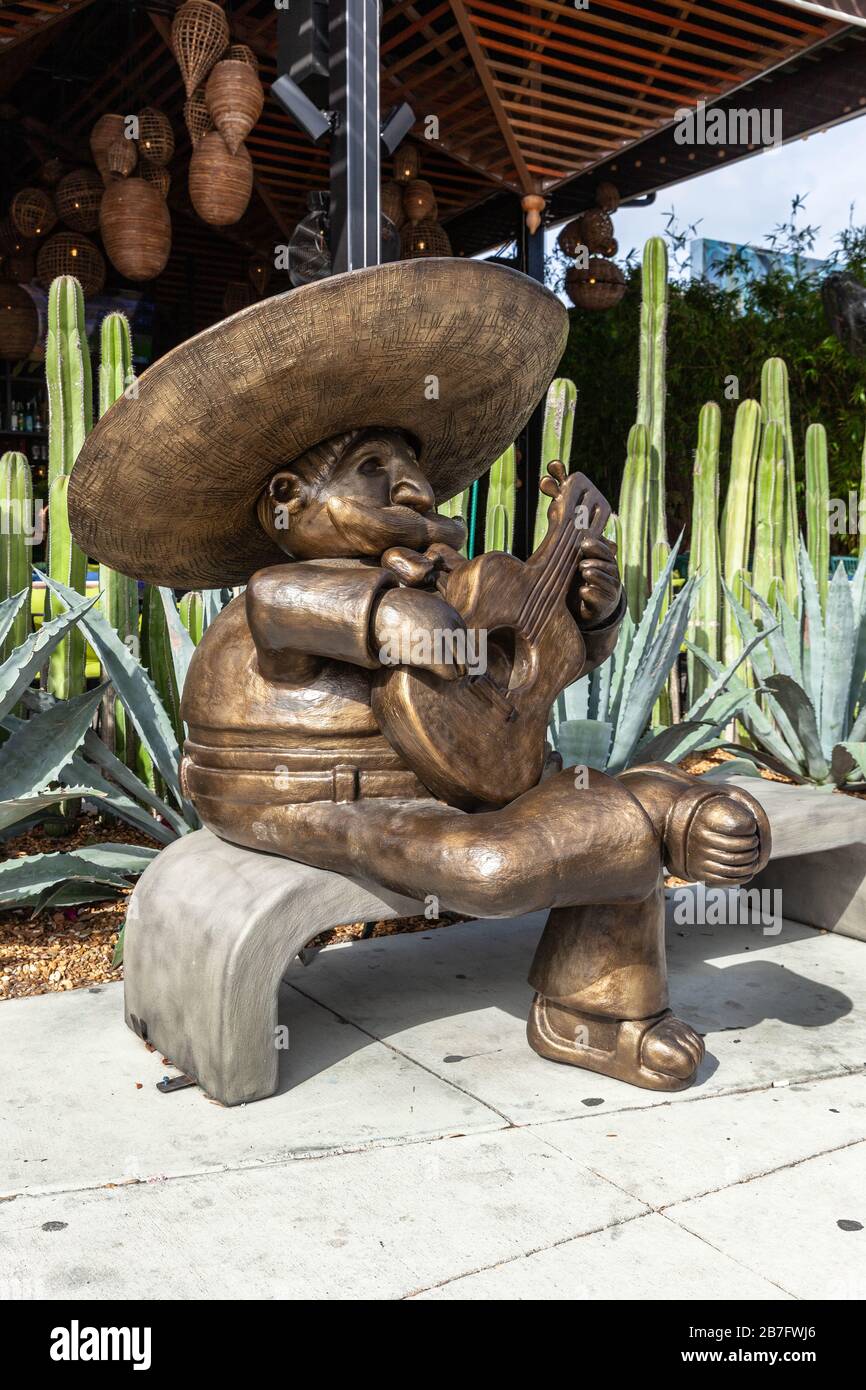 A life size wooden statue of a mariachi playing a guitar, while seated on a bench, Wynwood Art District, Miami, Florida, USA. Stock Photo