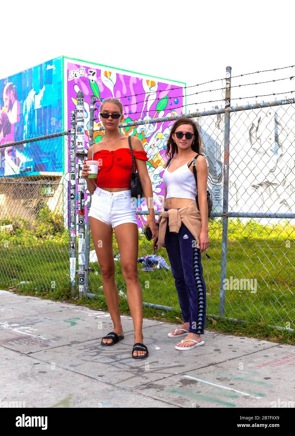 Full length portrait of two young women standing on a pavement, Wynwood art district, Miami, Florida, USA. Stock Photo