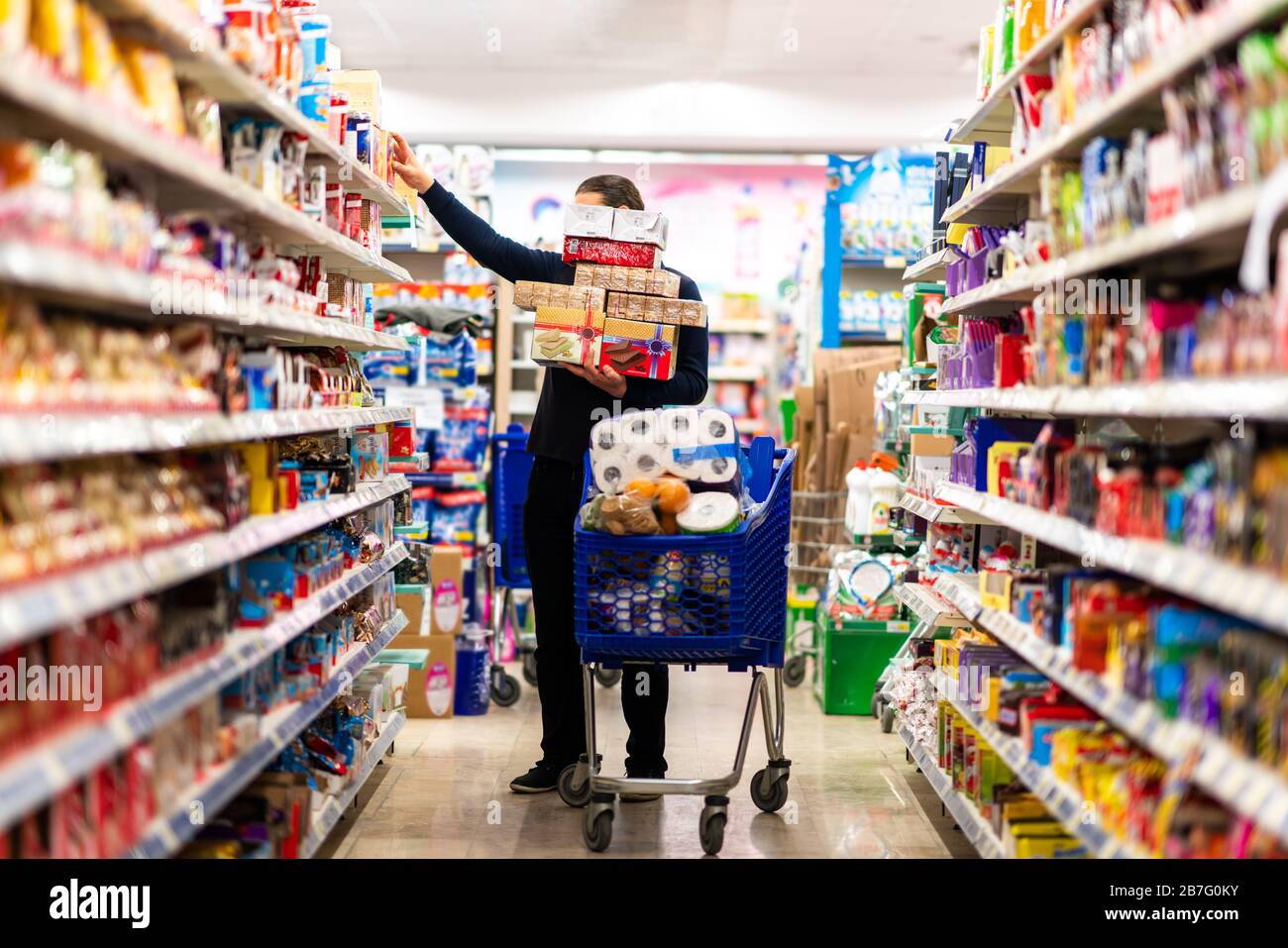 Full shopping cart, customer is stocking vital needs because of global chaos. Shopping with blur supermarket store products, interior background Stock Photo