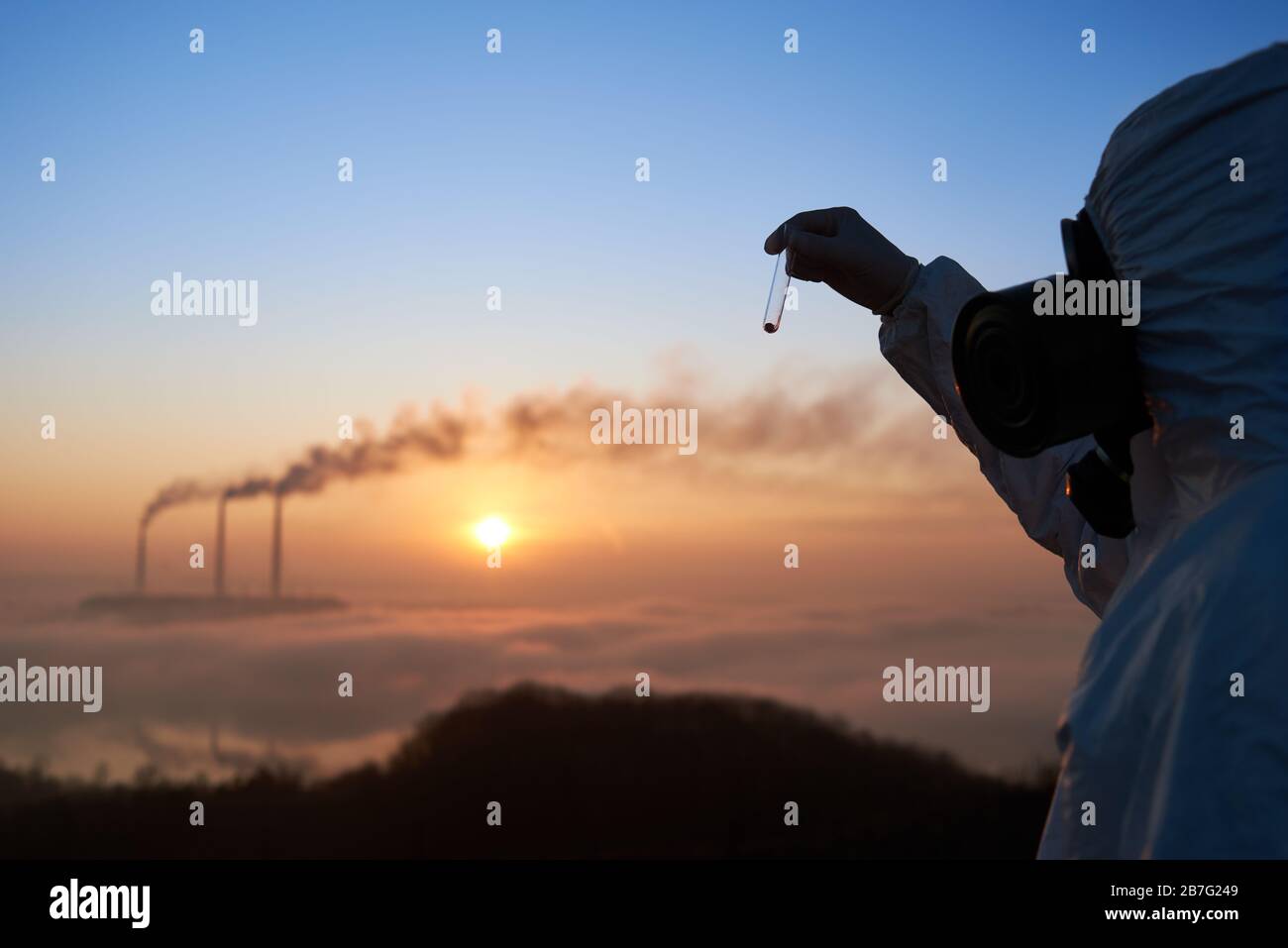 Ecologist in gas mask holding test tube with soil sample. Scientist exploring environmental