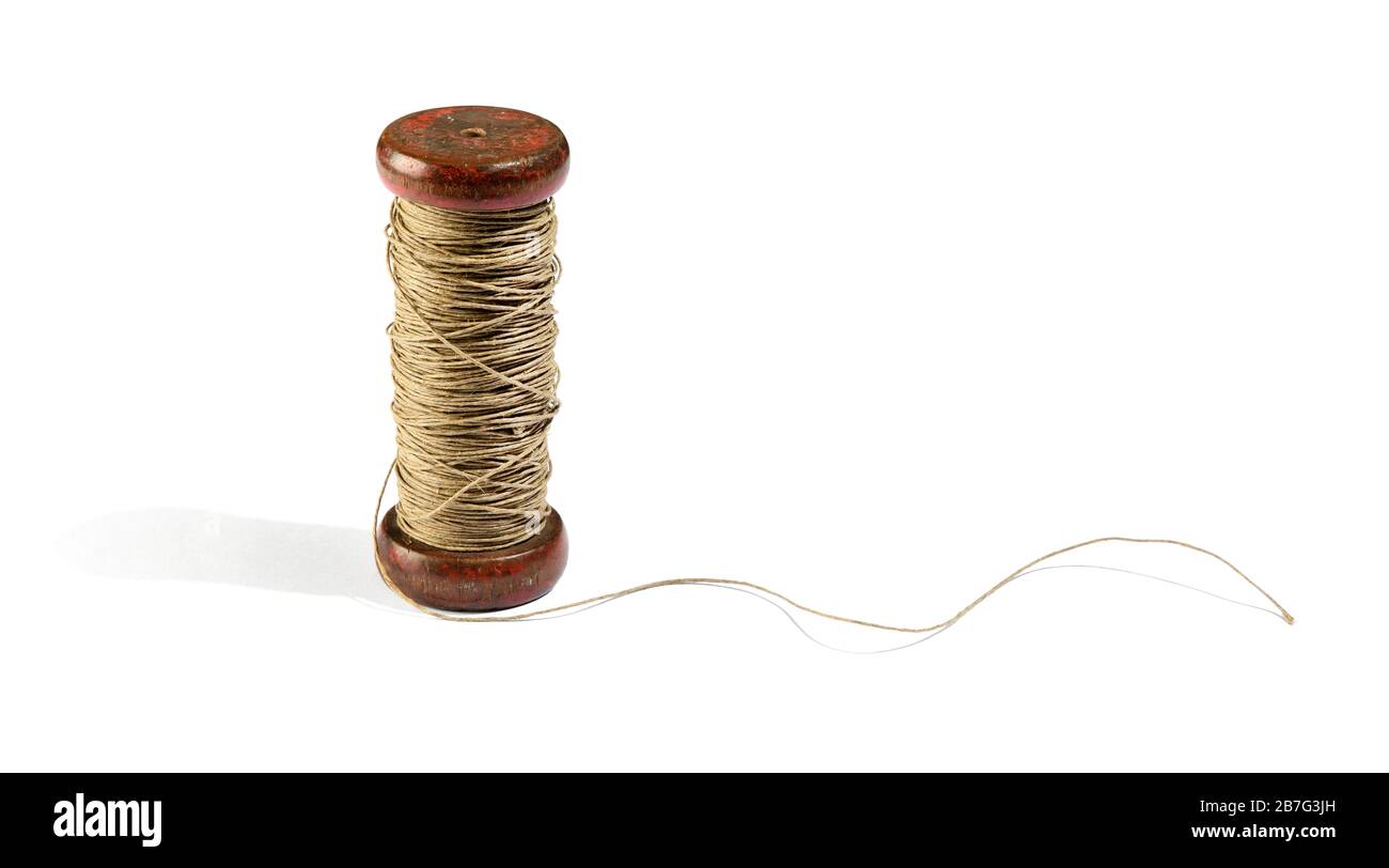 Vinatge wooden reel or spool of natural hemp twine or thread with the end unrolled standing upright over a white background with copy space Stock Photo