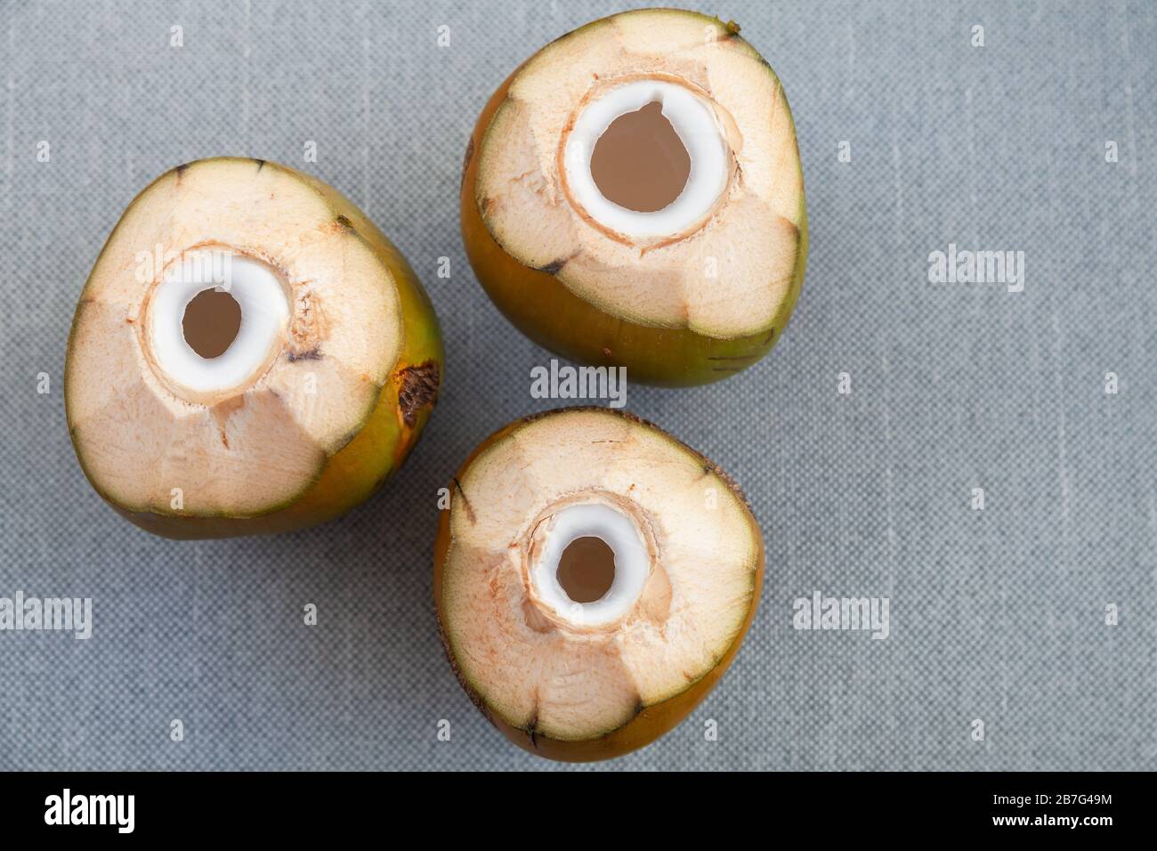 Three green coconuts with holes for straw stand on a gray surface, flat lay, top view photo Stock Photo